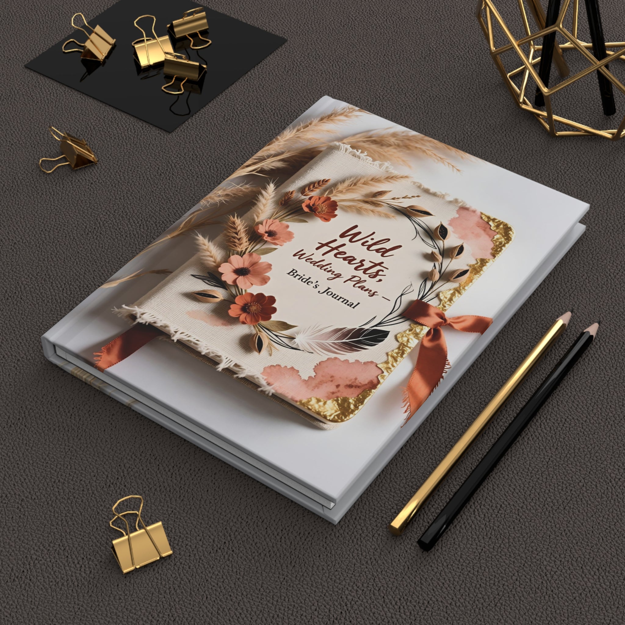 Decorative notebook with floral design on a dark surface with stationery items.