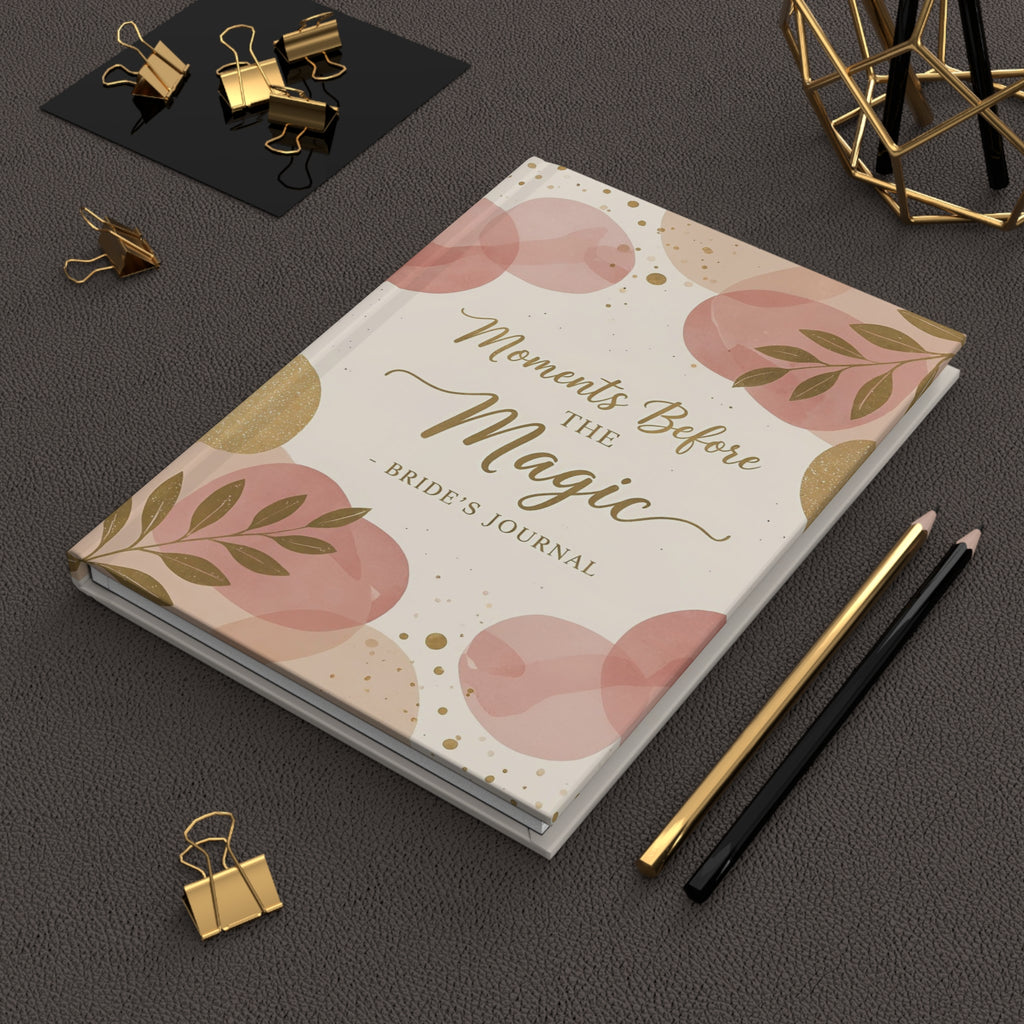 Bride's journal titled 'Moments Before The Magic' on a dark surface with decorative items.