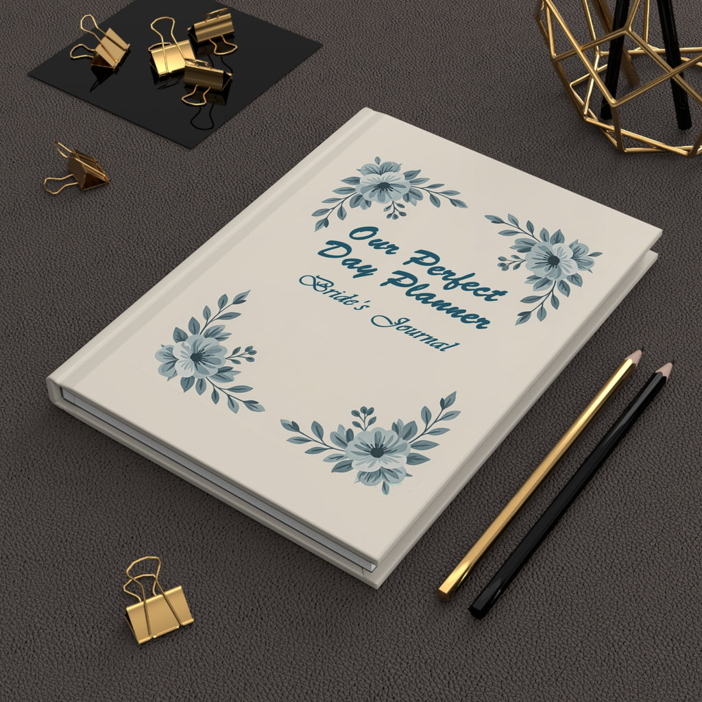 Day planner with floral design and text on a dark surface with office supplies.