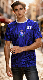 Man wearing a blue sports jersey with 'ES' logo on a blurred street background