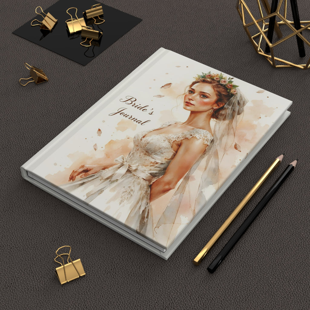 Journal titled 'Bride's Journal' with a bride illustration on a dark surface with stationery items.